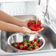 Woman is washing strawberry in the kitchen.