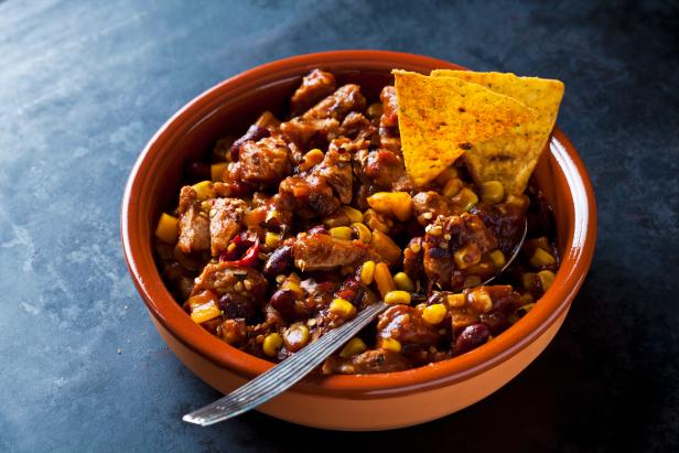 Chili con Soja Schnetzel, Tortilla Chips, Tonschale, gebraten, anbraten, gewürzt, soja, geschnetzelt, vegetarisch, Fleischersatz, Löffel, dunkler Untergrund,