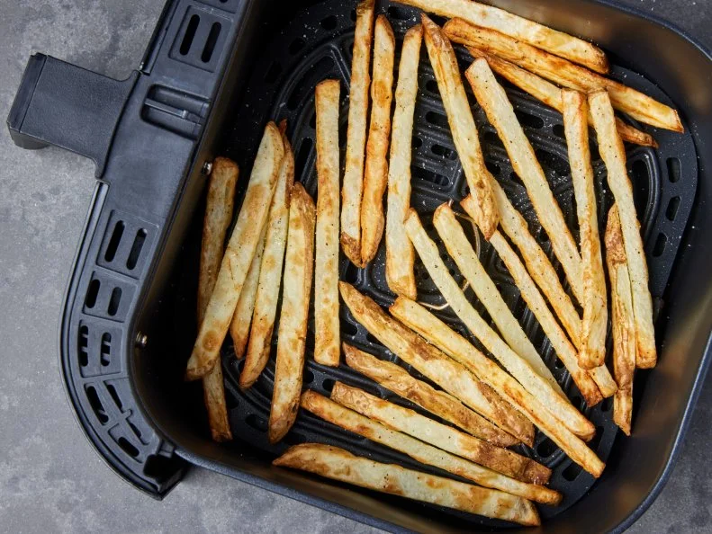 Photo showing air fryer basket open, shot into overhead, showing the way the fries look when they’re fully cooked for Air Fryer French Fries recipe, as seen on Food Network.