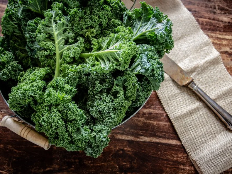 Green Kale in basket and knife on wooden  background top view on daylight superfood vegetables Still life