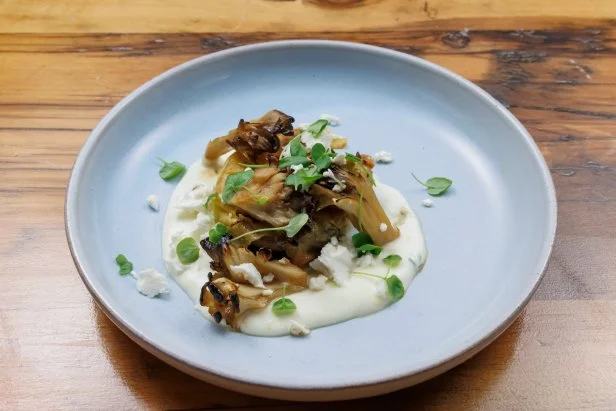 Pan fried börek surrounded by crema and topped with feta, greens, and mushrooms.