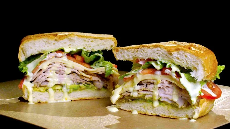 The Mojo Pork Torta uses beer brined pork loin with the Double IPA from Dancing Gnome Brewery called HaHa!. The Torta is layered with avocado, marinaded and spiced pork loin, pepper jack cheese, lettuce, tomato, and their very own house made citrus mayo, as seen on Burgers, Brew &  Que, Season 5.
