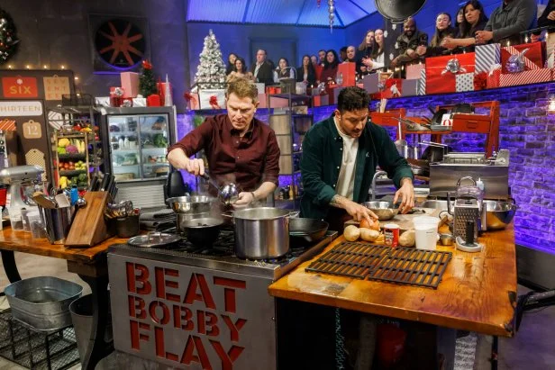 Chef Bobby Flay and contender Gabriele Bertaccini work on their Round 3 dishes, as seen on Beat Bobby Flay Holiday Throwdown, Season 4.