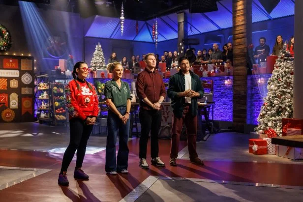 Contenders Claudette Zepeda and Brooke Williamson, chef Bobby Flay, and contender Gabriele Bertaccini await the results of Round 3, as seen on Beat Bobby Flay Holiday Throwdown, Season 4.