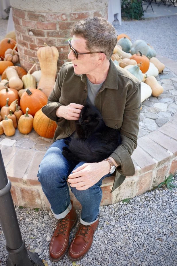 Bobby Flay pets a cat who lives on the grounds of Podere Il Casale in Tuscany, Italy, as seen on Bobby & Giada in Italy, Season 1. 