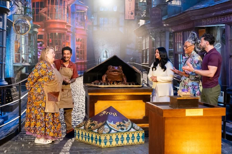 Judge Carla Hall and Judge Jozef Youssef and guest judge Afshan Azad with contestants Alex Madrigal and Jenny Chambers’ super sized showpiece the Chocolate Frog during judging, as seen on Harry Potter: Wizards of Baking, Season 2.