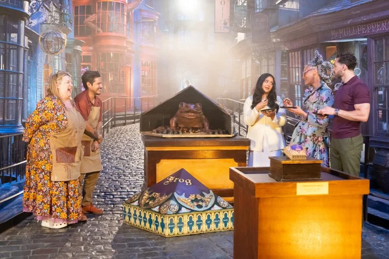 Judge Carla Hall and Judge Jozef Youssef and guest judge Afshan Azad with contestants Alex Madrigal and Jenny Chambers’ super sized showpiece the Chocolate Frog during judging, as seen on Harry Potter: Wizards of Baking, Season 2.
