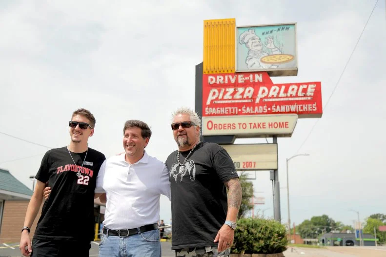 Host Guy Fieri and son, Hunter, pose with Charlie Peroulas outside Pizza Palace, located in Knoxville, TN, as seen on Guy's All-American Road Trip, Season 2.