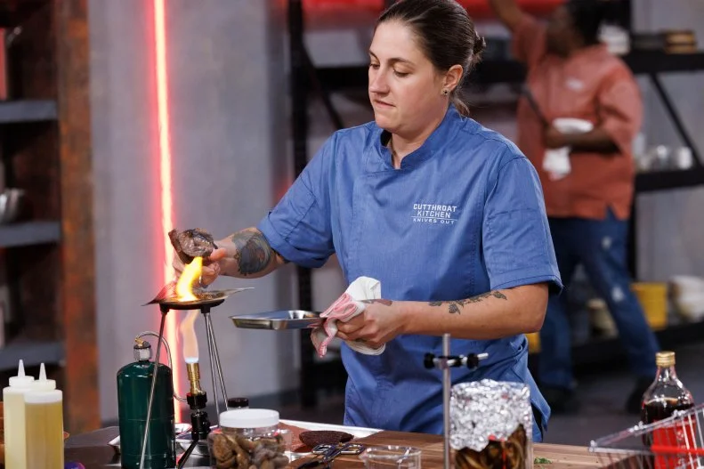Chef Shibumi Jones cooks with lab equipment after being sabotaged during round two, as seen on Cutthroat Kitchen: Knives Out, Season 1.
