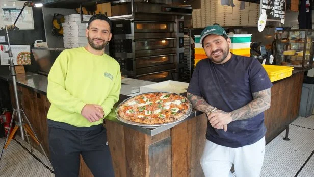 Behind the scenes of Massimo Laveglia and Nick Baglivo posing for the camera with the Burrata Pie between them.