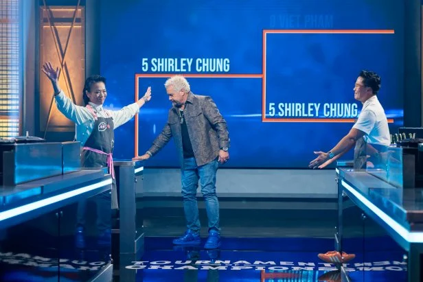 Host Guy Fieri and contestants Shirley Chung and Viet Pham react as Shirley Chung is announced the winner of the round, as seen on Tournament of Champions, Season 7.