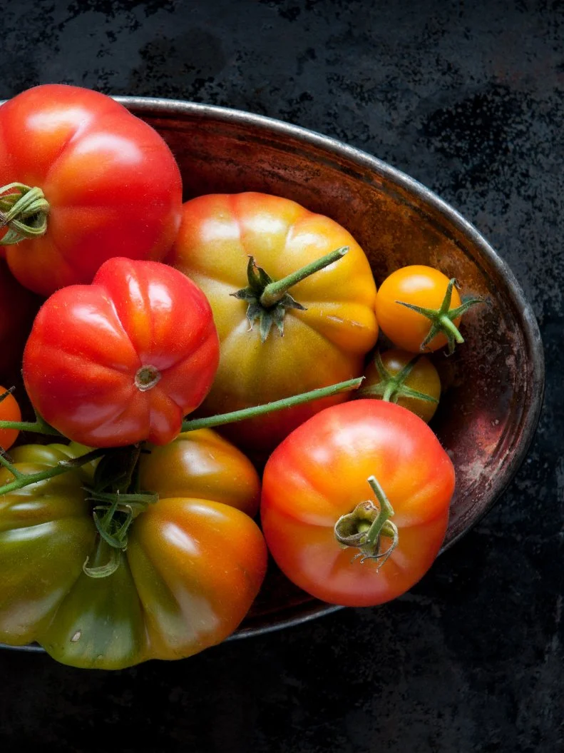 "An assortment of fresh, home grown, vine ripened heirloom tomatoes in a tarnished bowl against a dark, distressed background.  Organically grown.  View from above.More vegetables:"