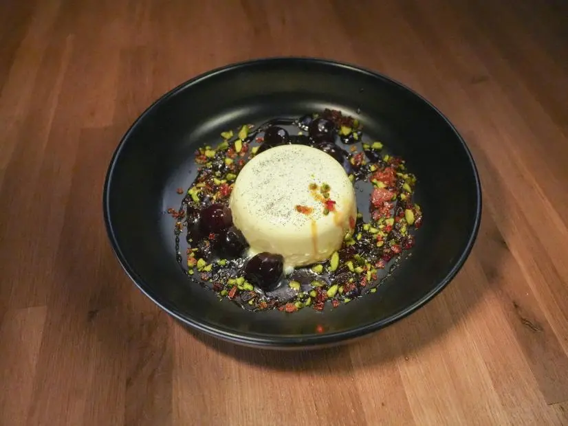 Food beauty shot of Todd Zimmerman's vanilla & cardamom panna cotta with amarena cherries & caramel brittle on Worst Cooks in America S29.