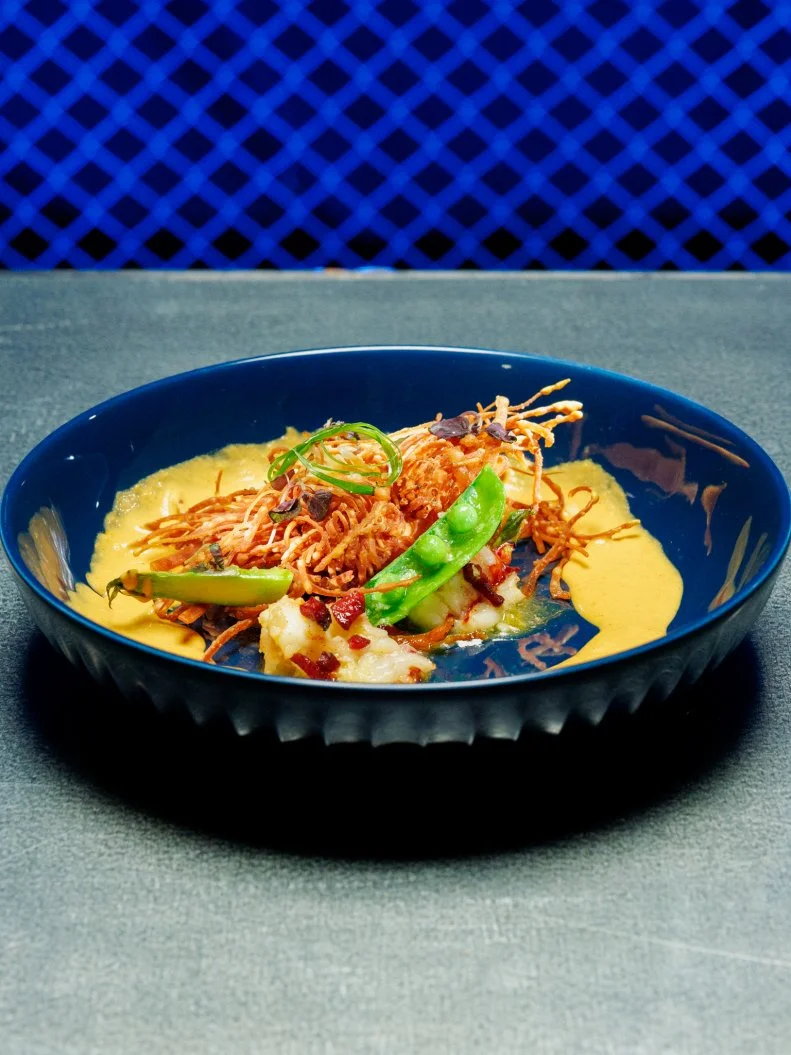 Contestant Joe Sasto beauty of dish - Lobster and Hot Dog Dumpling, poached lobster, crispy hot dog crouton, spring vegetables, served with hot dog curry, as seen on Chef Grudge Match, Season 1.