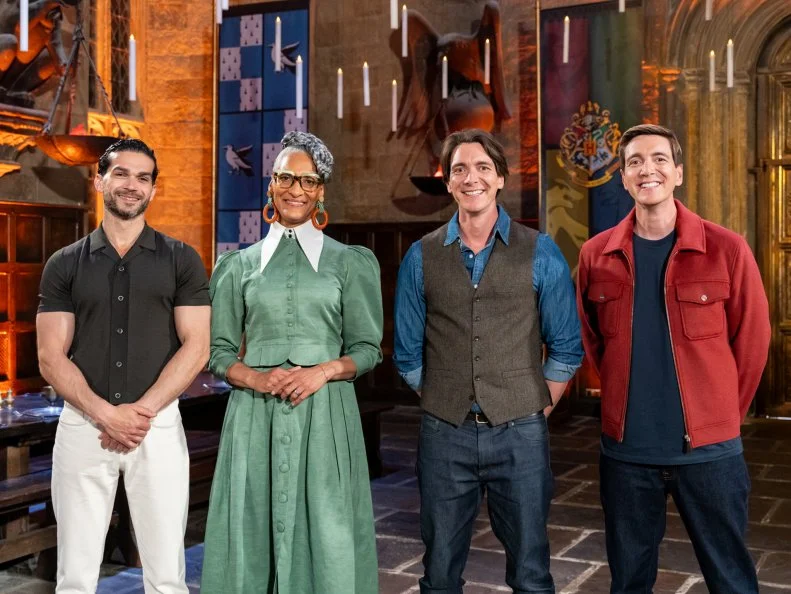 Judge Carla Hall and Judge Jozef Youssef and Hosts James and Oliver Phelps pose during judging, as seen on Harry Potter: Wizards of Baking, Season 2.