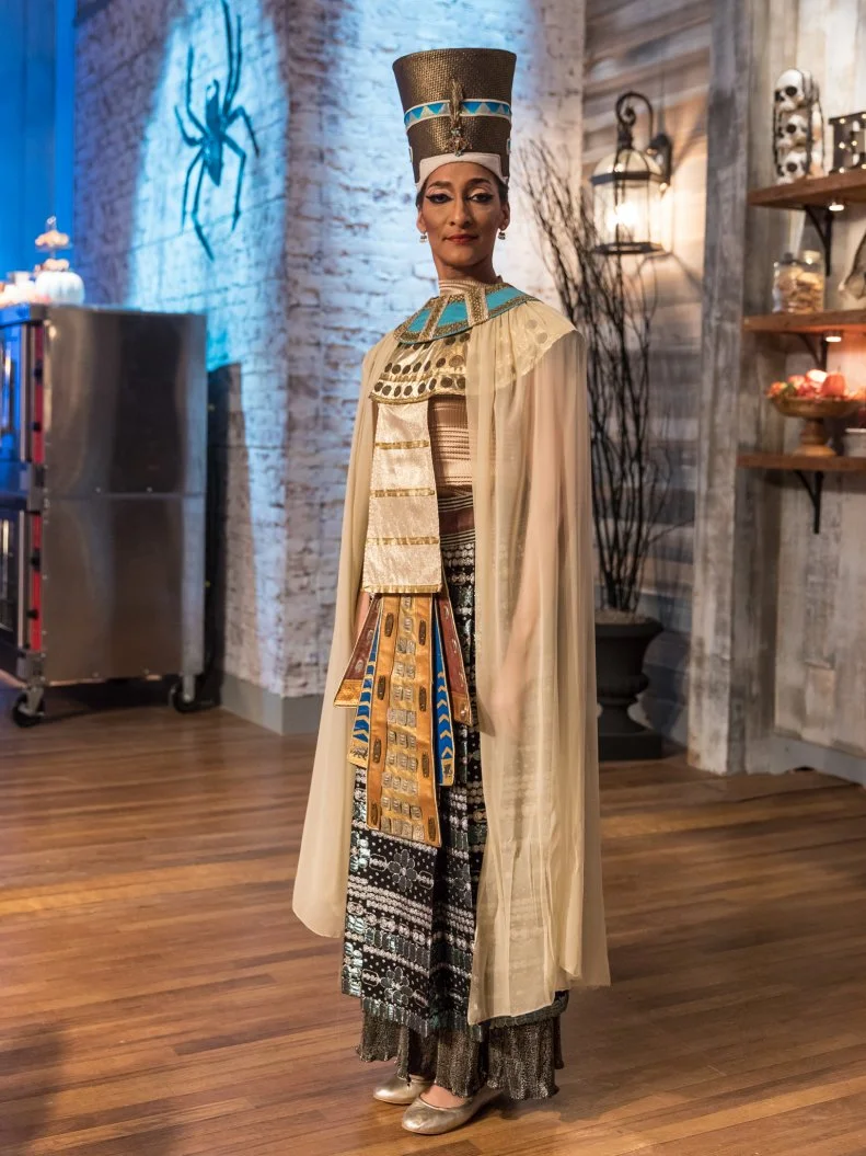 Judge Carla Hall in her Egyptian costume in a behind the scenes shot in the main heat, as seen on Food Network's Halloween Baking Championship, Season 3.