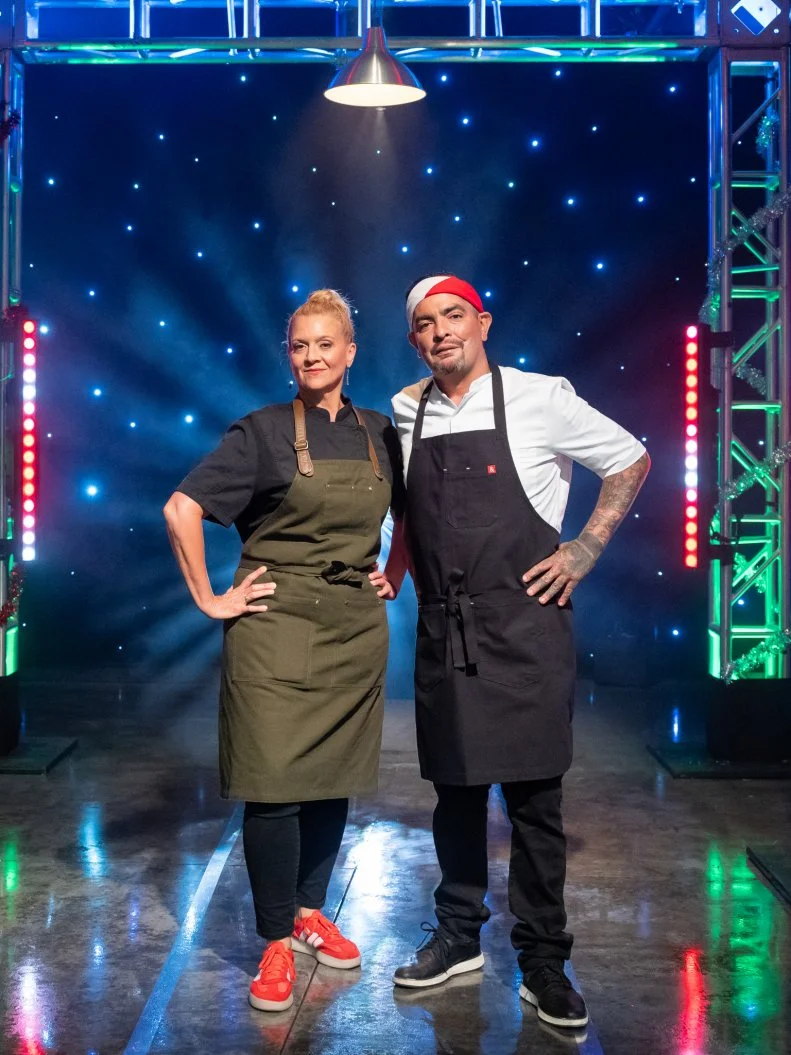 Contestants Amanda Freitag and Aaron Sanchez pose on set, as seen on Tournament of Champions Holiday, Season 1.