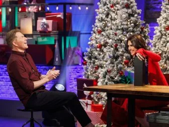 Chef Bobby Flay laughs with co-host Sophie Flay as she shows off some of the presents she's brought, as seen on Beat Bobby Flay Holiday Throwdown, Season 4.