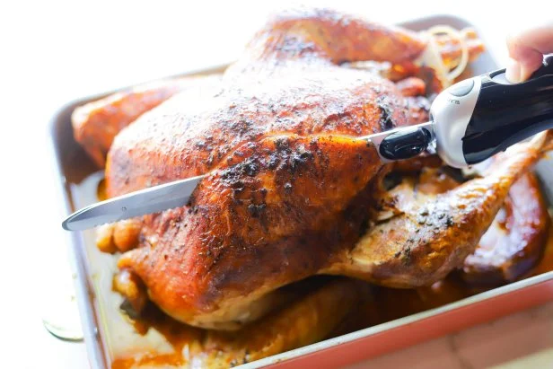 Electric knife cutting into whole turkey skin