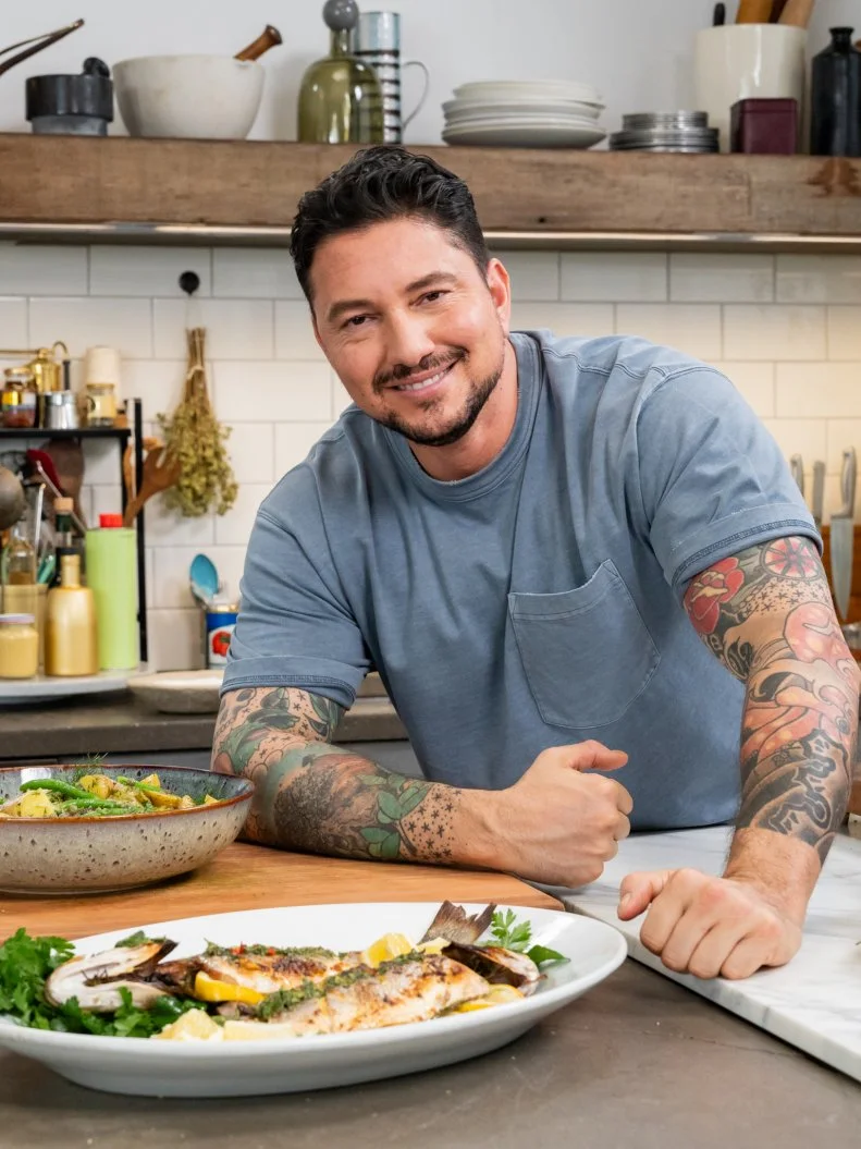 Host Gabe Bertaccini posed with Roasted branzino with salmoriglio and Pantelleria potato salad, as seen on Cook Like an Italian with Gabe Bertaccini, Season 1.