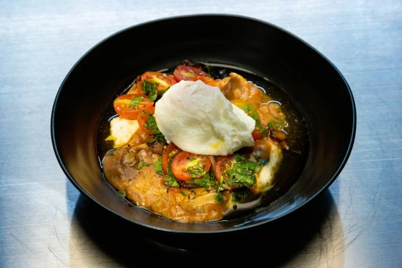 Contestant Austin Sumrall's round 2 dish, Grits and Grillades.Stone ground grits with grilled corn, holy trinity, braised pork, sauteed oyster mushrooms, cherry tomato and herb salad with a poached egg, as seen on Alex vs America, Season 3.