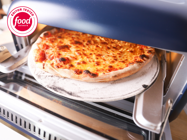Cheese pizza coming out of a navy blue pizza oven