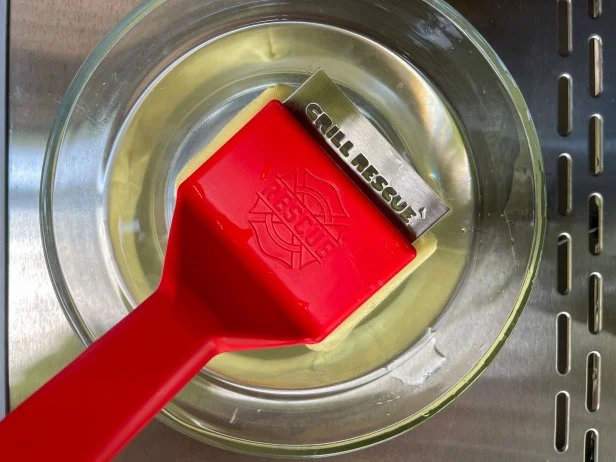 The Grill Rescue Bristle-Free Steam Cleaning Grill Brush being prepared to use by being dipped into a bowl of water