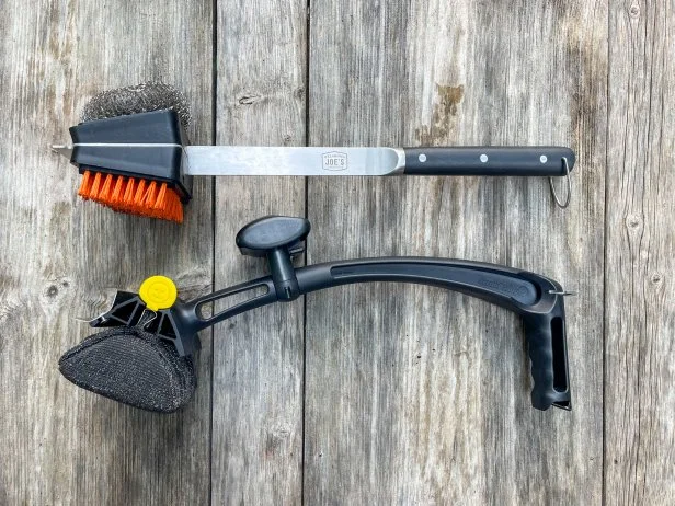 The Oklahoma Joe's grill brush and Scrub Daddy BBQ Daddy grill brushes sitting on a wooden outdoor table