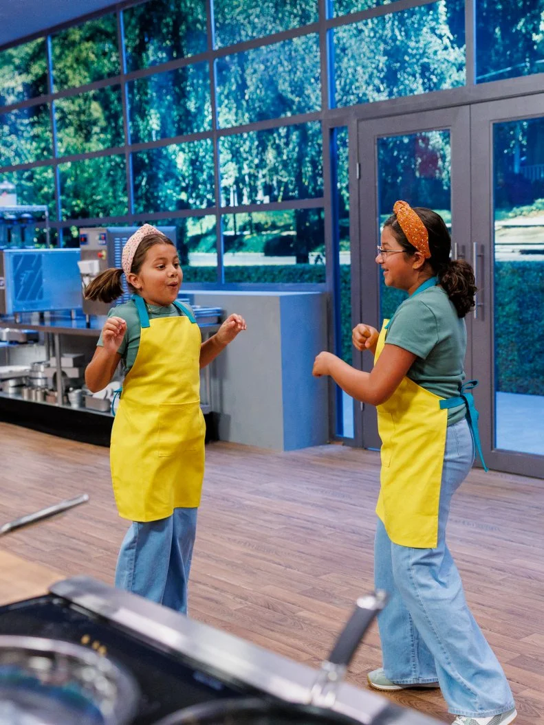 Contestants Kavya and Taanvi Bhenderu are presented with a dance off challenge, winner receives 5 extra minutes on their bake, as seen on Baking Championship: Next Gen, Season 1.