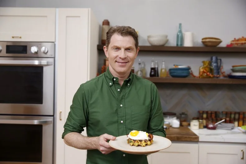 Chef Bobby Flay smiles while holding the finished dish, as seen on Food Network's Beat Bobby Flay, Season 7.