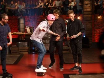 Contender Pablo Zitzmann and co-Hosts Michael Voltaggio and Tony Hawk watch chef Bobby Flay ride his skateboard on set of Beat Bobby Flay, Season 20.