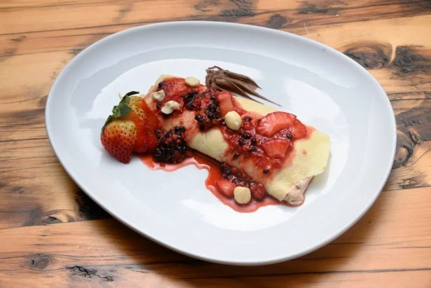 A Swedish pancake topped with strawberries, blackberries, and hazelnuts.