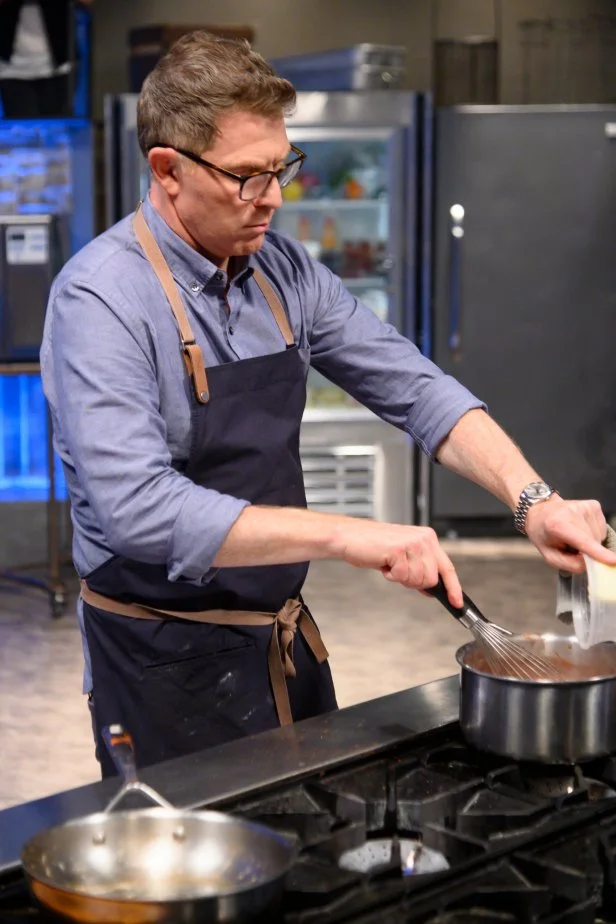 Bobby Flay khuấy pudding sô cô la trên bếp với vẻ quyết tâm cao độ.