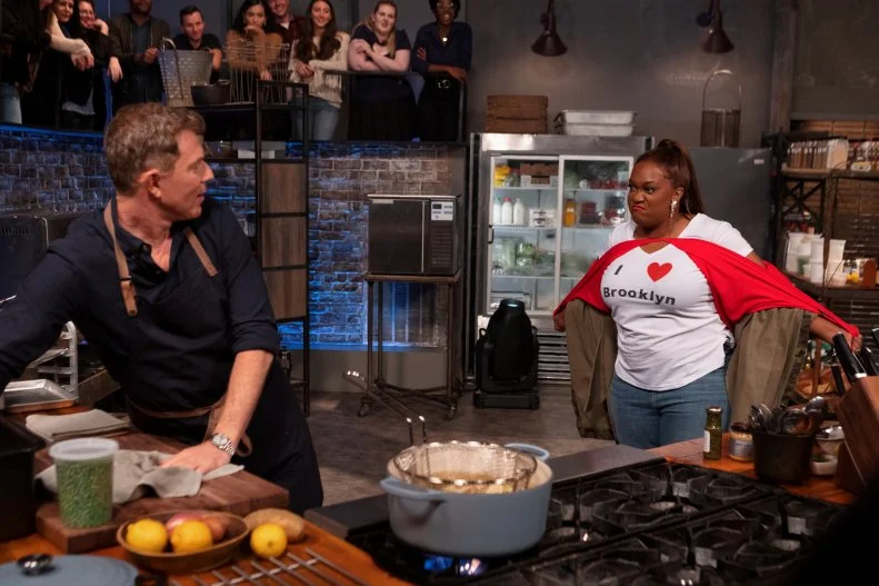 Co-host Sunny Anderson rips open her “I Love Bobby” t-shirt to show Bobby Flay the “I Love Brooklyn” t-shirt beneath underneath it as he cooks during round two, as seen on Beat Bobby Flay, Season 30.