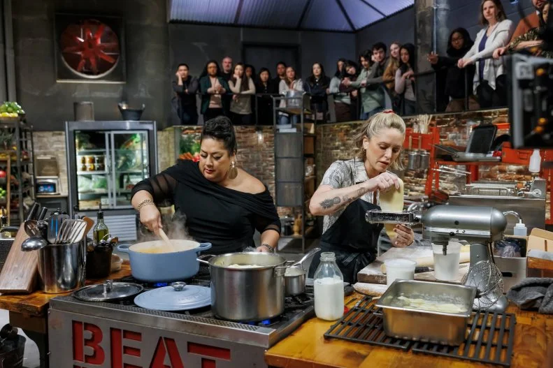 Co-host Ayesha Nurdjaja stirs sauce for Brooke Williamson's Round 2 dish, as seen on Beat Bobby Flay, Seaon 41.