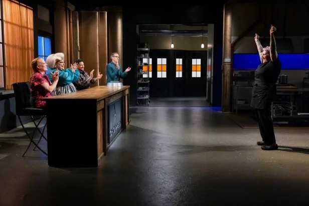 Jenn Strange Standing In Front of Judges With Arms Raised