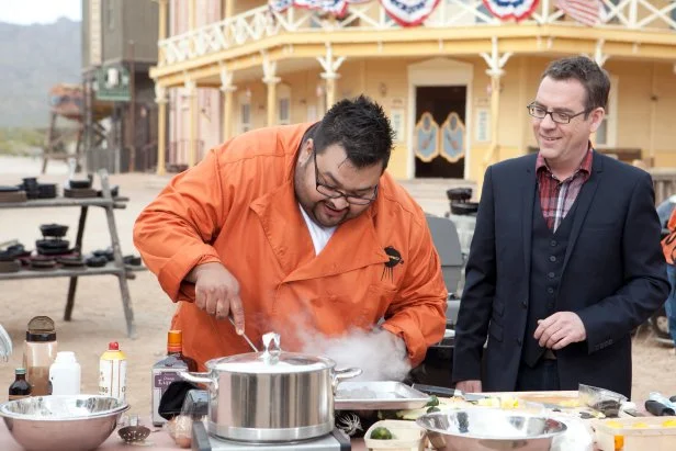 Chopped host Ted Allen talking to Chef Ernest Servantes while he works on his dessert that must include: meyer lemons, marshmallows, charcoal biscuits and zucchini on day three of the Chopped $50K Grilling Challenge in Tucson AZ, as seen on Food Network's, Chopped Season 12.