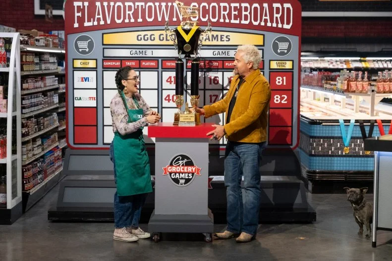 Host Guy Fieri presents the Guy's Grocery Games Global Games trophy to winner Claudette Zepeda, as seen on Guy's Grocery Games, Season 41.