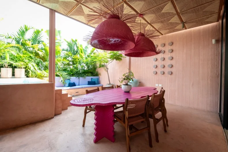 The outdoor spaces in Rick Martinez's home flow easily from the inside and are also connected with a shared design sensibility from the handmade palm woven tiles on the ceiling to the bright pink and merlot colors.