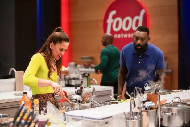 Molly Yeh cooking, Eddie Jackson walking by and Eric Adjepong (l ro r), as seen on Food Network wildcard kitchen season two.