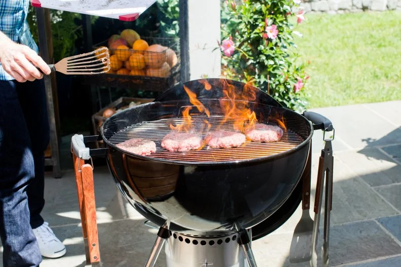 Chef Bobby Flay places his burger patties on a hot charcoal grill, as seen on Bobby Flay's Barbecue Addiction.