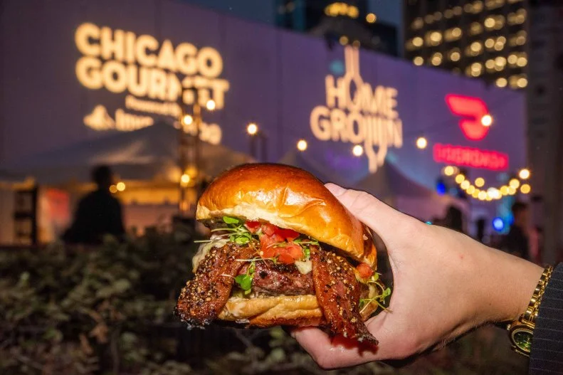Someone holding a hamburger from the Hamburger Hop event at the Chicago Gourmet food festival