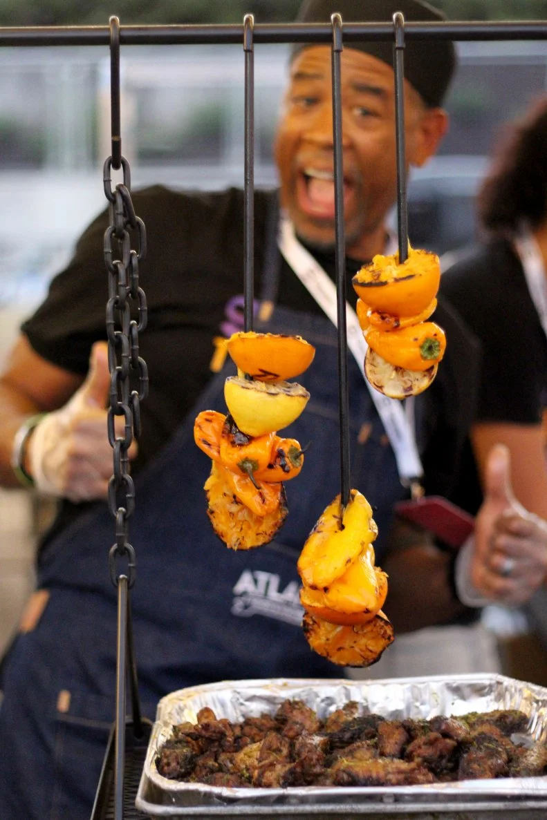 A chef standing behind a row of skewers of sliced vegetables