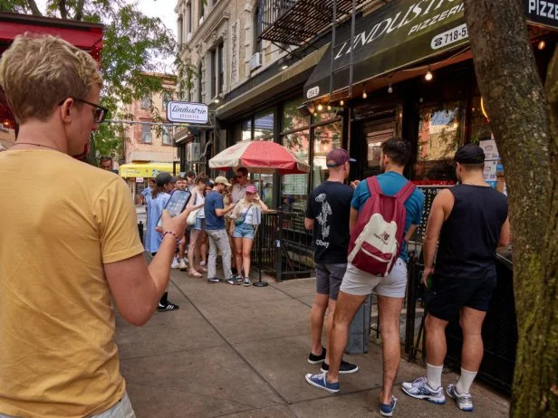 Customers stand in line outside of L'industrie Pizzeria in Brooklyn, New York.