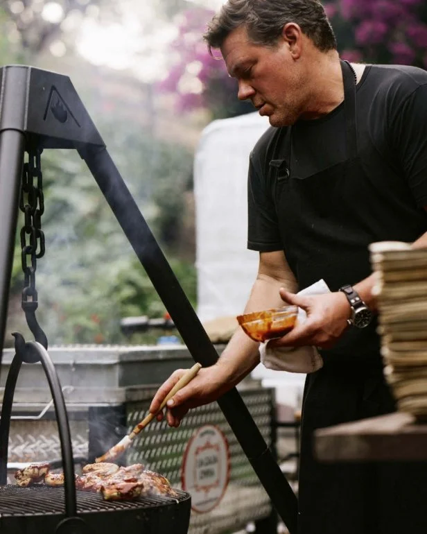 Chef Tyler Florence brushes chicken on a standing grill rack.