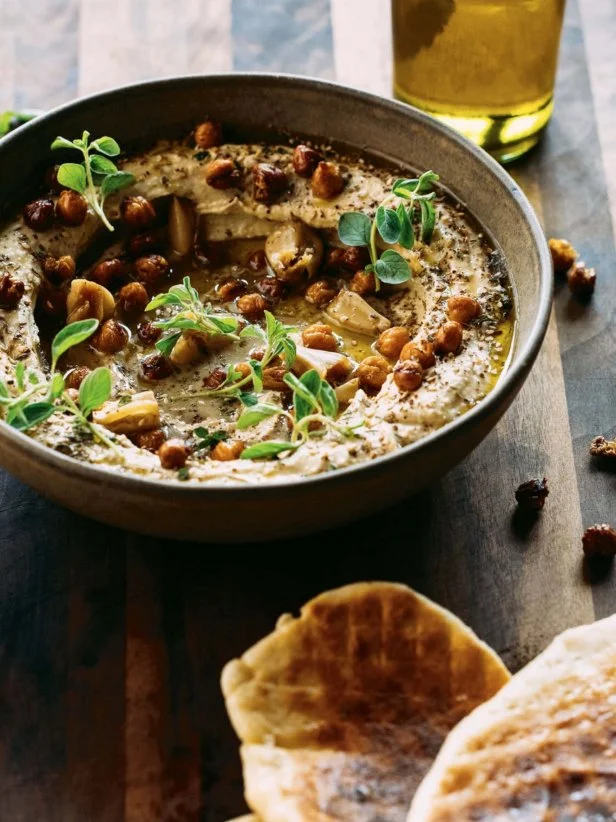 Bowl of miso hummus on wooden tabletop.