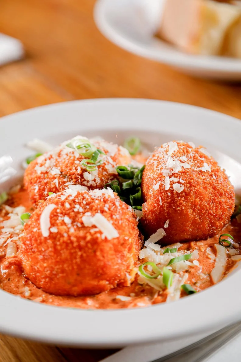 Balls of fried pasta served with shredded cheese and pink sauce