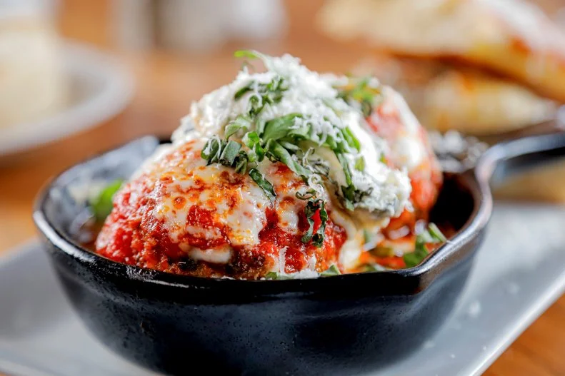 A pair of large meatballs in a cast iron skillet