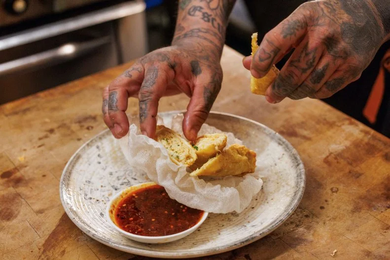 Aaron Sanchez plating Chili Crisp Crab Spring Rolls dish in kitchen