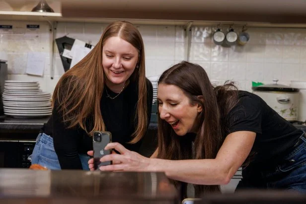 Jen Agg and Jenna N bend to take a picture of the food